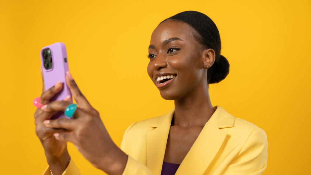 Une femme souriant devant un téléphone portable